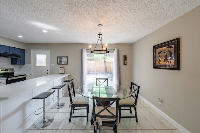 dining room with light tile patterned floors, a textured ceiling, baseboards, and an inviting chandelier