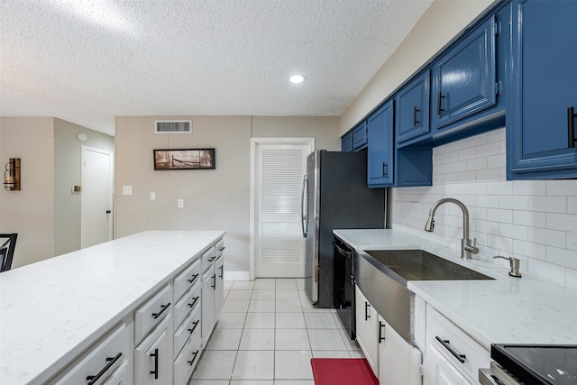 kitchen featuring visible vents, light tile patterned flooring, black dishwasher, blue cabinets, and tasteful backsplash