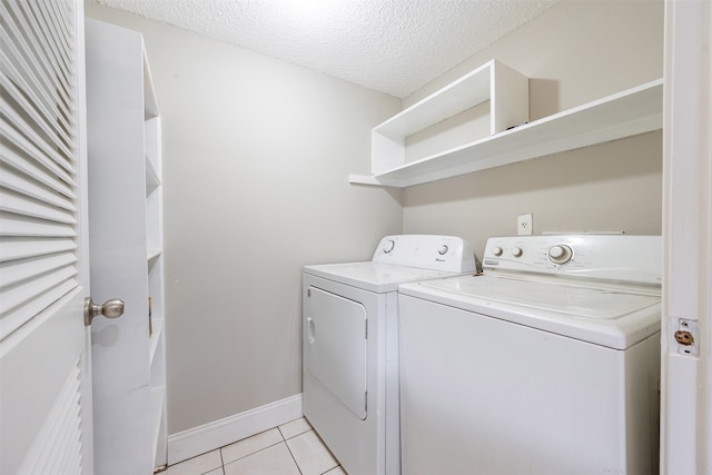 laundry area with baseboards, laundry area, light tile patterned flooring, a textured ceiling, and washer and dryer