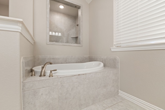 bathroom featuring tile patterned floors, a bath, and baseboards