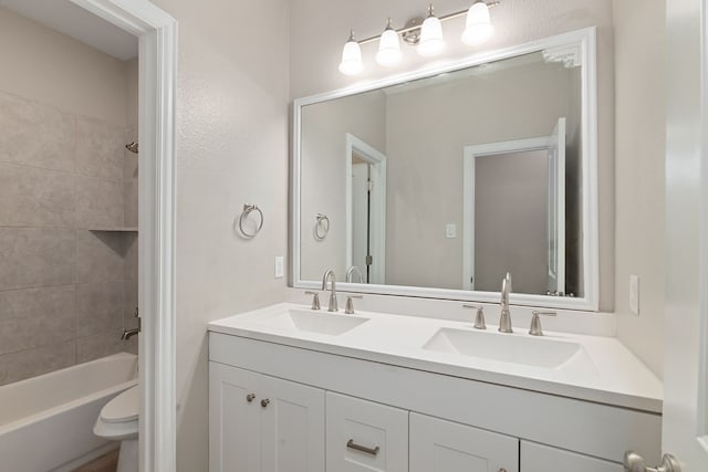 bathroom featuring bathtub / shower combination, double vanity, toilet, and a sink