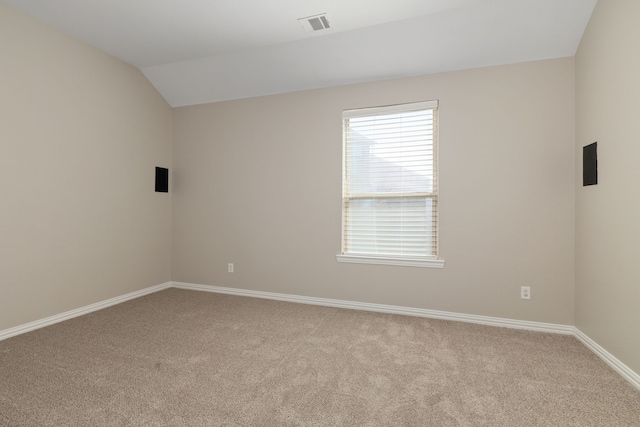 carpeted empty room featuring visible vents, baseboards, and vaulted ceiling