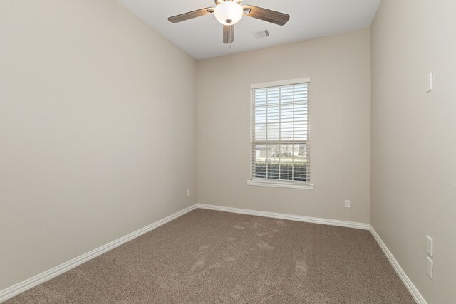 carpeted spare room with visible vents, baseboards, and ceiling fan