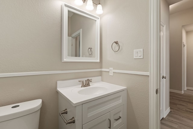 bathroom with toilet, wood finished floors, and vanity