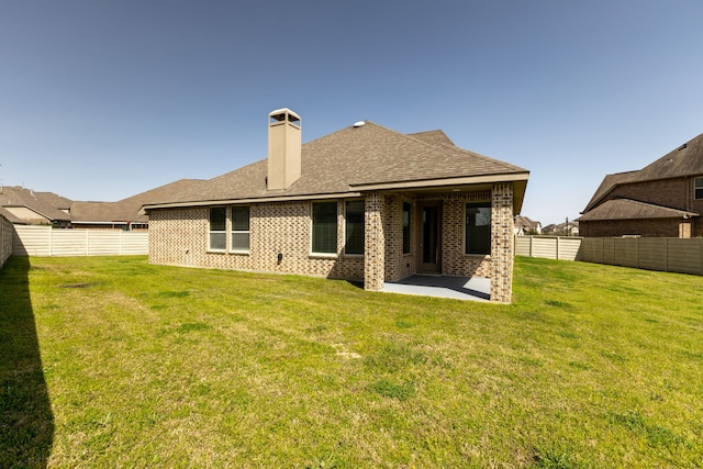 rear view of property featuring a lawn, brick siding, and a fenced backyard