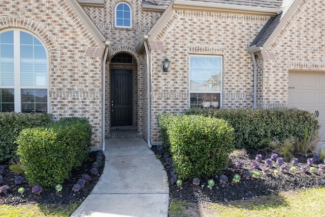 property entrance featuring a garage and brick siding