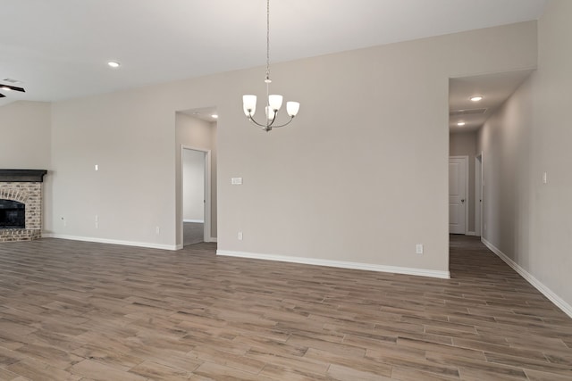 unfurnished living room featuring baseboards, a brick fireplace, and wood finished floors