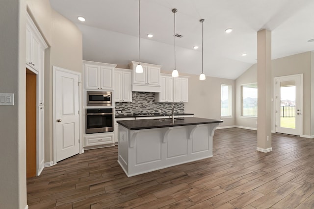 kitchen with a sink, dark countertops, white cabinetry, appliances with stainless steel finishes, and decorative backsplash