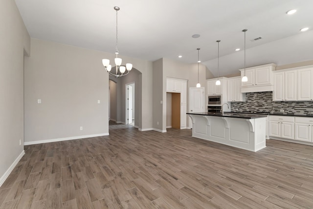 kitchen featuring dark countertops, tasteful backsplash, arched walkways, and light wood finished floors