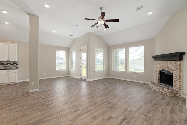 unfurnished living room featuring plenty of natural light, a fireplace, visible vents, and light wood-type flooring