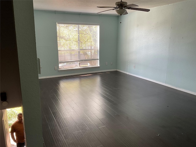 unfurnished room featuring dark wood finished floors, baseboards, and a ceiling fan