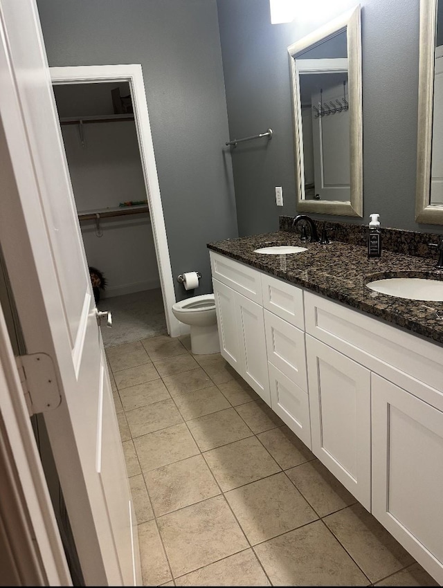 bathroom featuring tile patterned flooring, double vanity, toilet, and a sink