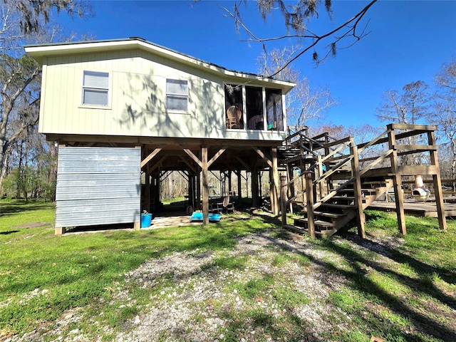 rear view of house with stairs, a yard, and a sunroom