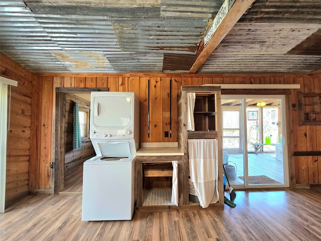 laundry area featuring laundry area, stacked washer / dryer, wood finished floors, and wood walls