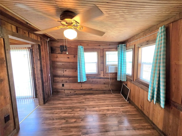 spare room featuring wooden walls, wood ceiling, dark wood finished floors, and a ceiling fan