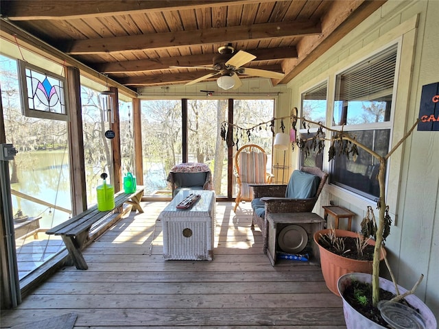 sunroom / solarium featuring beamed ceiling, wooden ceiling, and a ceiling fan