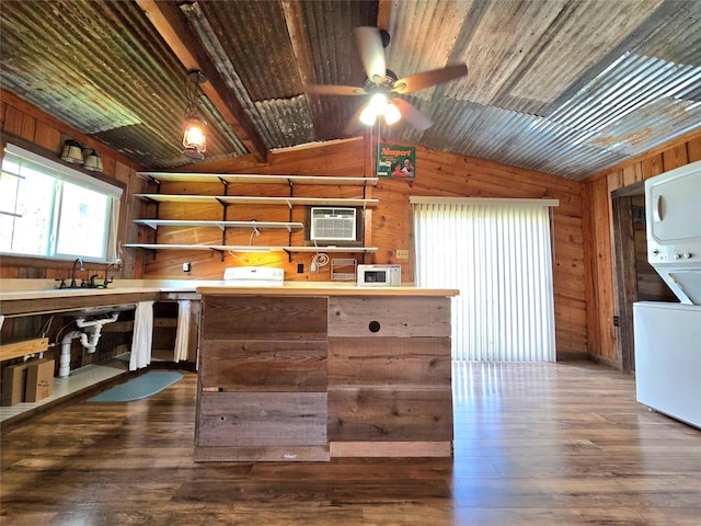 kitchen with stacked washer and clothes dryer, wood walls, dark wood finished floors, and vaulted ceiling