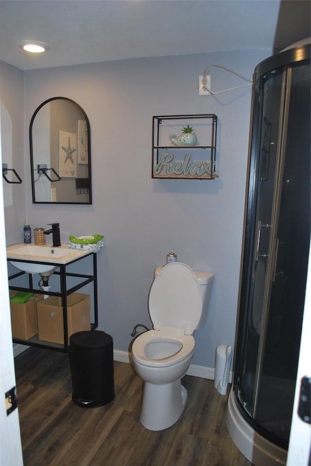 bathroom with wood finished floors, a stall shower, and baseboards