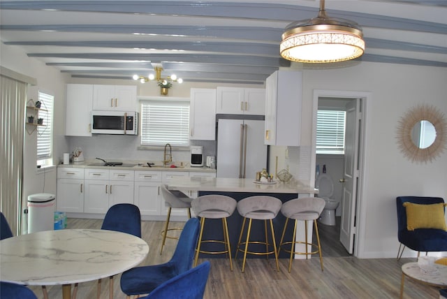 kitchen with backsplash, white cabinetry, black electric cooktop, white microwave, and high end refrigerator