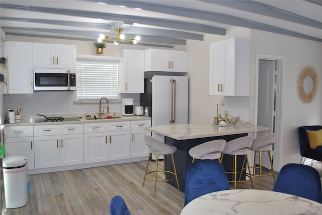 kitchen featuring light stone countertops, light wood finished floors, a sink, white cabinetry, and a kitchen bar