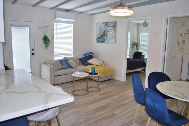 living area featuring baseboards, light wood-style floors, and a wall mounted AC