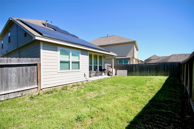 back of house featuring a lawn, solar panels, and a fenced backyard