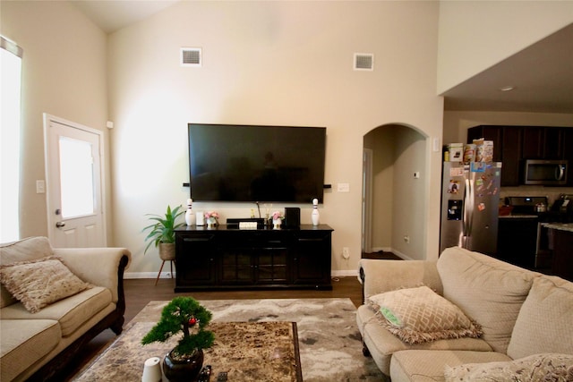 living area with visible vents, arched walkways, baseboards, and wood finished floors