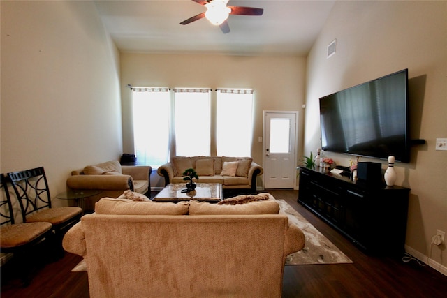 living area featuring a ceiling fan, visible vents, baseboards, dark wood-style flooring, and vaulted ceiling