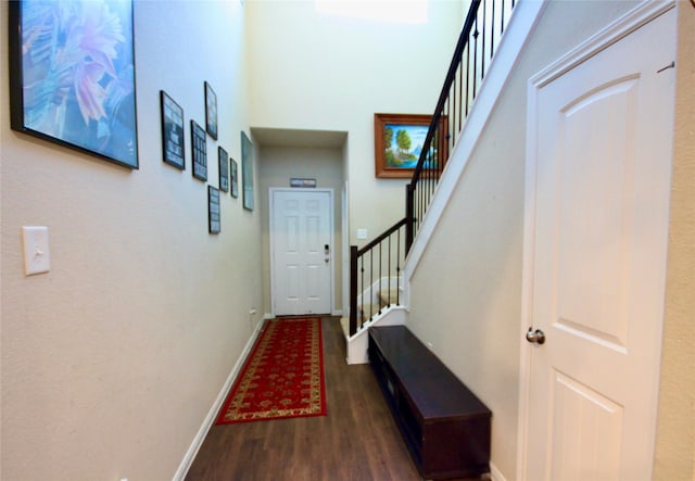 interior space with a high ceiling, stairway, wood finished floors, and baseboards