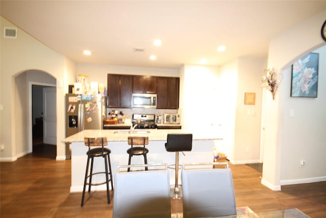 kitchen with visible vents, dark wood finished floors, decorative backsplash, arched walkways, and stainless steel appliances