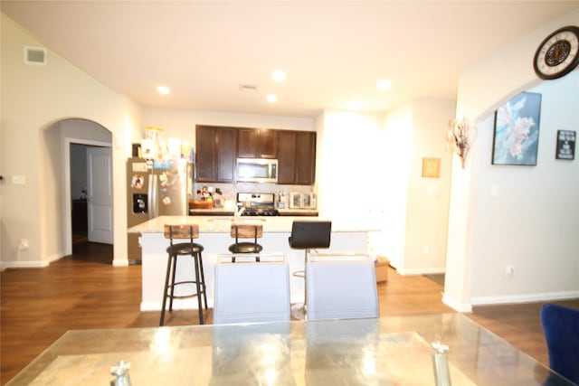 kitchen with visible vents, arched walkways, light countertops, appliances with stainless steel finishes, and a kitchen bar