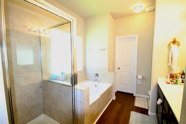 bathroom with vanity, a bath, wood finished floors, a stall shower, and toilet