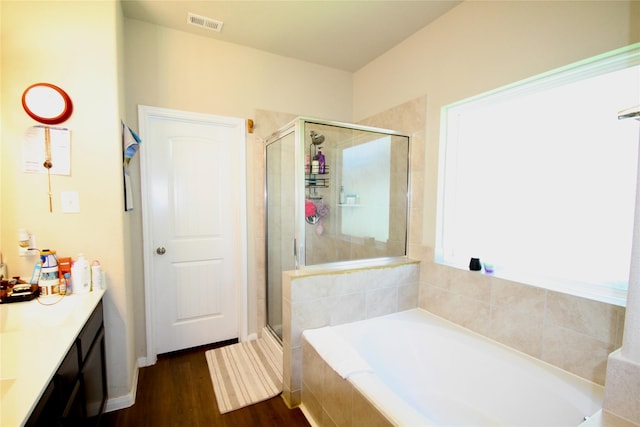 bathroom featuring vanity, wood finished floors, visible vents, a stall shower, and a garden tub