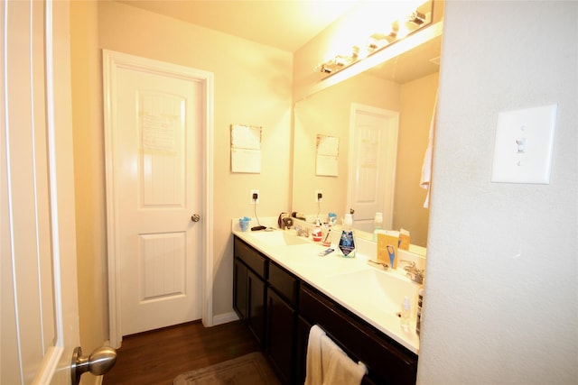 bathroom with double vanity, wood finished floors, and a sink