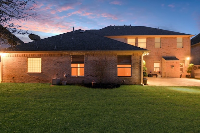 back of house with a yard, brick siding, and a patio area