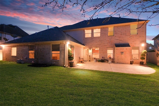 rear view of house with a yard, brick siding, and a patio area