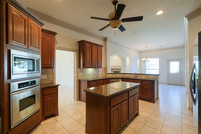 kitchen featuring a kitchen island, dark stone counters, a sink, decorative backsplash, and stainless steel appliances