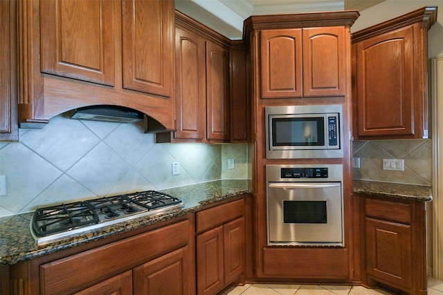 kitchen with dark stone counters, backsplash, and appliances with stainless steel finishes