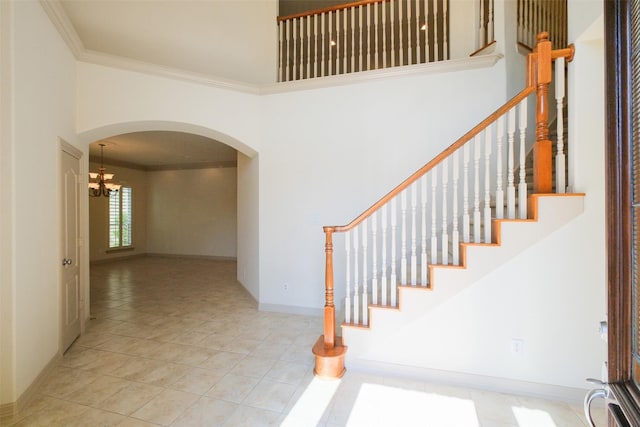 stairway with tile patterned flooring, baseboards, ornamental molding, a high ceiling, and arched walkways