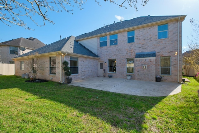 rear view of property featuring a yard, fence, brick siding, and a patio area