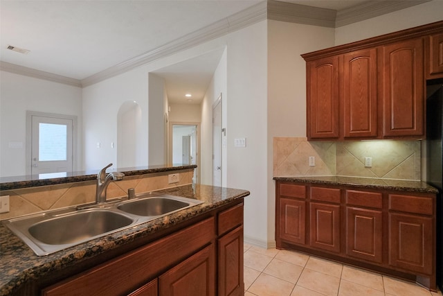 kitchen featuring visible vents, backsplash, light tile patterned floors, arched walkways, and a sink