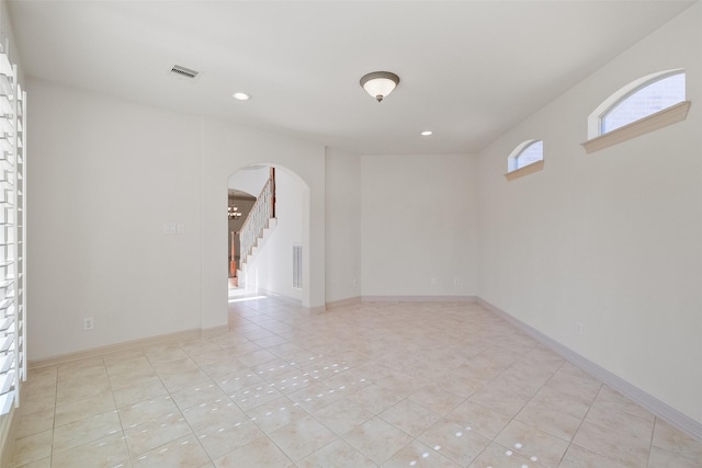 spare room with visible vents, baseboards, light tile patterned floors, recessed lighting, and arched walkways