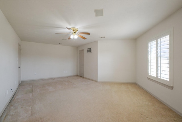 spare room featuring light carpet, visible vents, baseboards, and ceiling fan