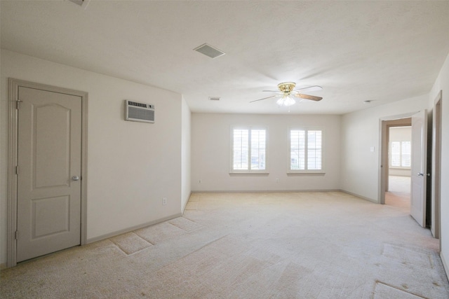 spare room with a ceiling fan, plenty of natural light, and light colored carpet