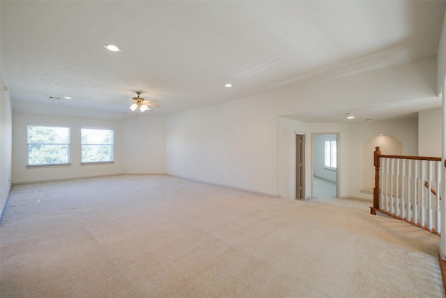 unfurnished room with plenty of natural light, light colored carpet, and a ceiling fan