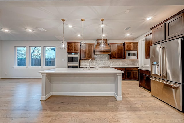 kitchen with visible vents, backsplash, appliances with stainless steel finishes, light countertops, and custom exhaust hood