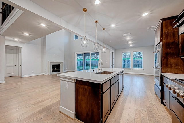 kitchen featuring visible vents, dark brown cabinets, light countertops, a fireplace, and a sink