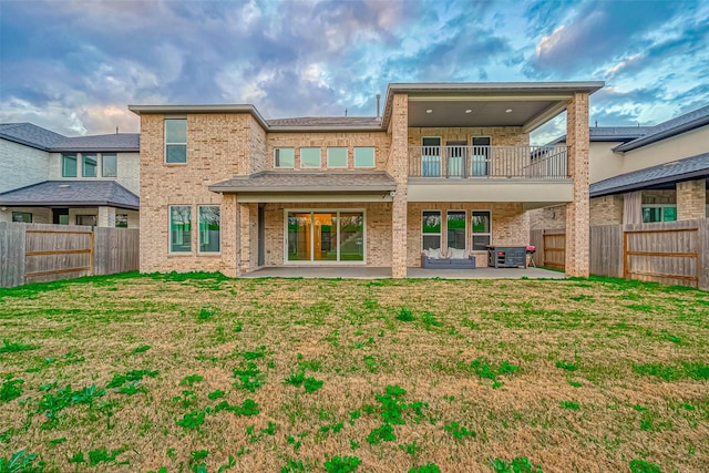 back of property featuring a patio, a balcony, a fenced backyard, and brick siding