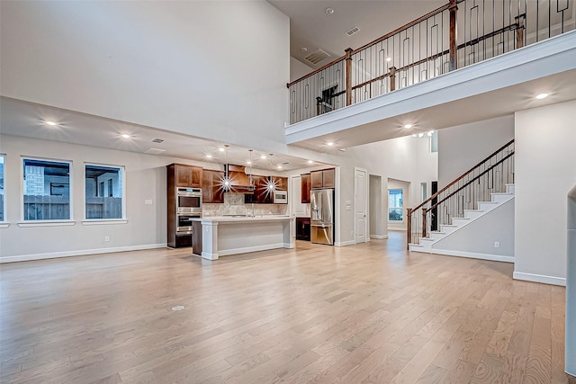 unfurnished living room featuring recessed lighting, stairs, light wood-type flooring, and baseboards