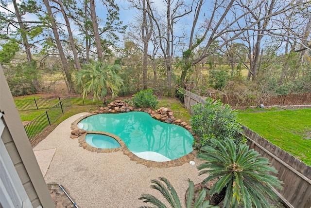 view of swimming pool with a yard, a pool with connected hot tub, and a fenced backyard